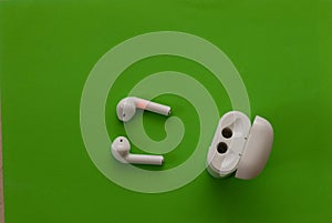 Small white wireless headphones near their holster - photo