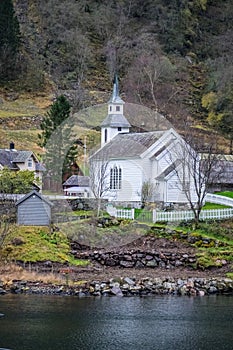 Small white wooden church on a fjord shore