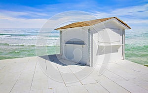 Small white wooden cottage with thatched roof by the sea