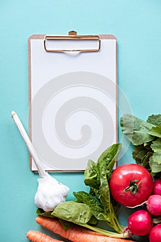 Small whiteboard with vegetables around on blue background. Copy space. Healthy concept.