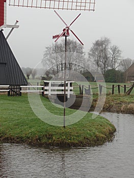 Small wind turbine in front of a traditional windmill