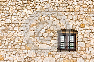 A small window of a dungeon with a lattice and a stone wall with