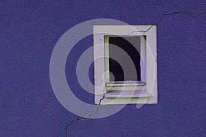 Small window of a house with a broken wall in lilac color