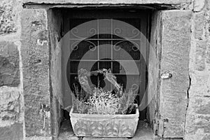 Small window in a medieval stone wall with floral decoration in black and white