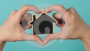 Small wood house in hands represent concepts such as home care family love