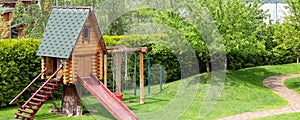 Small wood log playhouse hut with stairs ladder and wooden slide on children playground at park or house yard. Panoramic