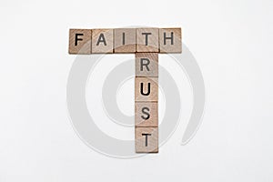 small wood squares with letters creating crossword puzzle spelling words Faith and trust