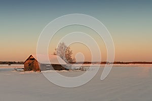 Small Wooden Barn House In the winter Sunrise