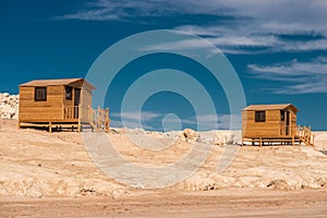 Small wooden bathing house on a white sandy beach.