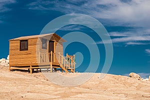 Small wooden bathing house on a white sandy beach.