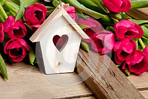 Small wooden bird house with heart decoration on etro wooden background, photo