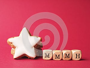 Small wooden blocks with the inscription mmmh next to a cinnamon star on a red background