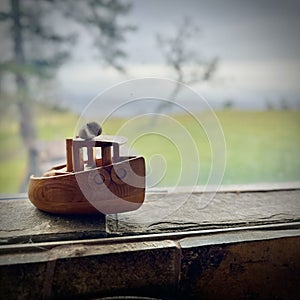 a small wooden boat is sitting on the windowsill overlooking the lake