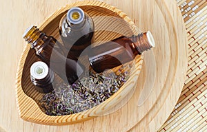 Small wooden bowl with dry lavender and bottles with essential oil. Aromatherapy  homemade spa  natural hair care concept.