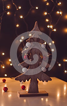 Small wooden christmas tree with bokeh lights in the background