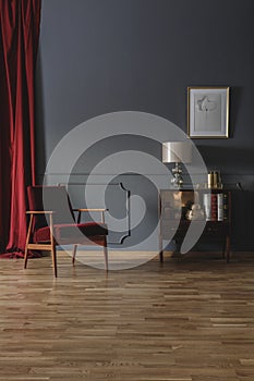 Small wooden cupboard with books, decor and lamp placed in grey