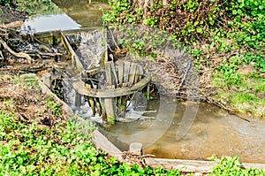 Small wooden dam on mountain river, forest and green grass