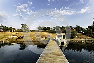 Small wooden dock and a boat on the lake under a blue sky and sunlight at daytime