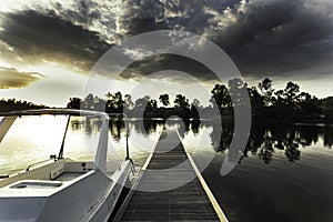 Small wooden dock and a boat on the lake under a cloudy sky during the sunset in the evening