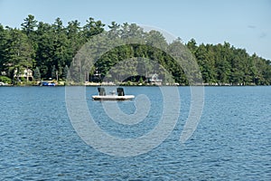 Small wooden dock floats on the calm waters of New Hampshire's Lake Winnipesaukee