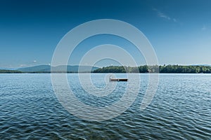 Small wooden dock floats on the calm waters of New Hampshire's Lake Winnipesaukee
