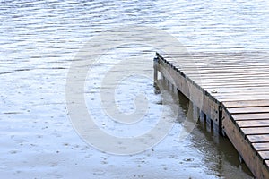 Small wooden dock leading out to a lake wet under heavy rainfall