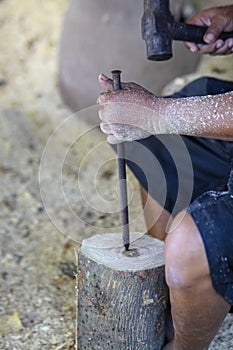A small wooden drumA drummer uses a hammer to sharpen the wood to guide the drum.