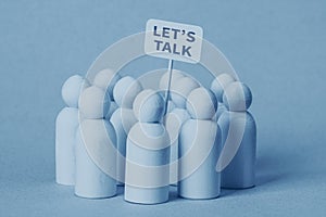 Small wooden figures with a Let's Talk poster