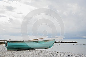 Small wooden fishing azure boat on pebble coast black sea beach