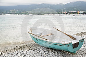 Small wooden fishing azure boat on pebble coast black sea beach