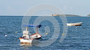 Small wooden fishing motorboat floating on blue sea water near coastline