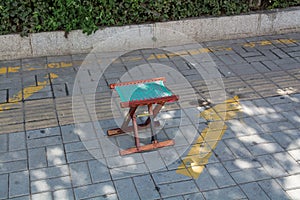 Small wooden folding stool stay alone on a pavement.