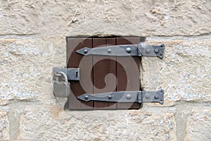 Small wooden hinged door with padlock in a stone wall