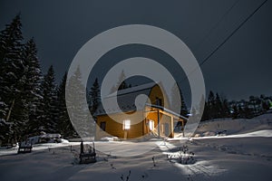 Small wooden house in the Carpathians, on the background of the winter forest at night