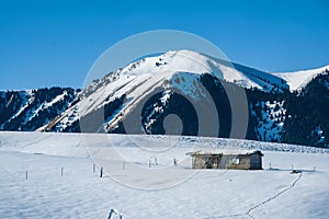 Small wooden hut at the foot of the snow-covered Tianshan Mountains in winter