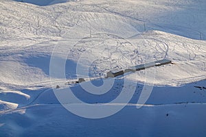 Small wooden hut at the foot of the snow-covered Tianshan Mountains in winter