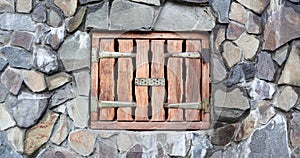 Small Wooden Loading Door in Wall of Old Stone Barn. Ancient Stone Wall with Small Strong Wooden Door. Miniature small antique