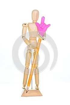 Small wooden mannequin holding a pencil with an eraser hand making the sign of the horns, isolated on white background