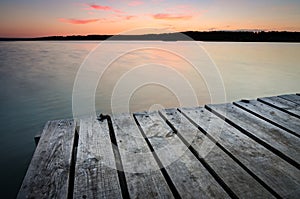 Small wooden pier on big lake at sunset