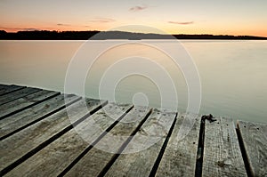 Small wooden pier on big lake at sunset