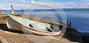 A small wooden rowboat on the shoreline