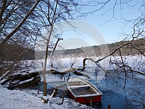 Small wooden rowboat in a snowy lake in winter