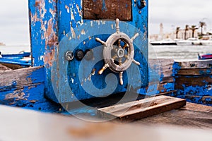 Small wooden rudder of a beached boat aged and abandoned on the shore of the sea