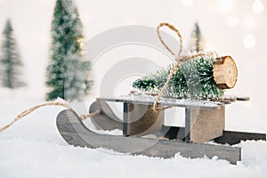 Small wooden sleigh with a Christmas tree in the snow