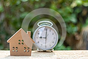 Small wooden toy house alarm clock on wooden table in the morning.