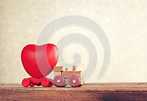 Small wooden toy locomotive carries heart, valentine`s day card