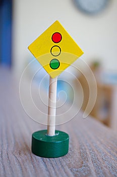 Small wooden traffic light sign on the wooden table under the lights with a blurry background