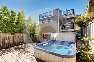 Small Wooden walkout deck with hot tub. House exterior.