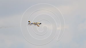 Small yellow Airplane flying in an extreme acrobatics exhibition