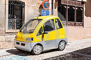 Small yellow electric car parked on street